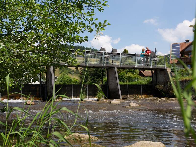 Ein Wanderpaar steht auf einer Brücke über die Kinzig in Schenkenzell.