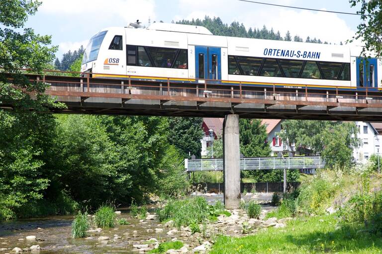 Ein Zug fährt über eine Brücke über die Kinzig.